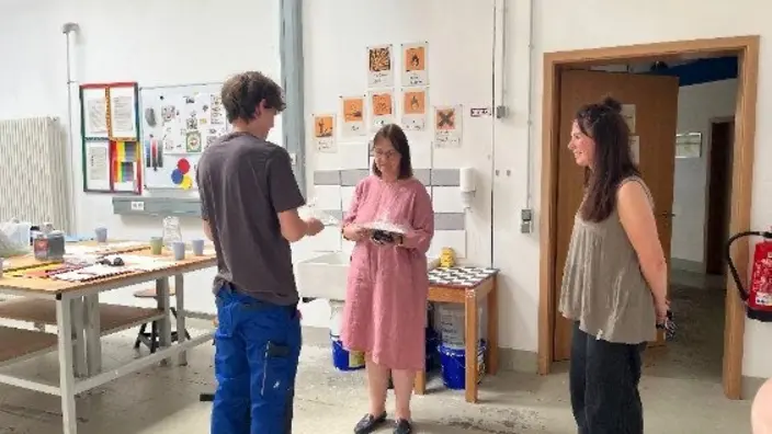 Azubi überreicht Geschenk von Malern und Lackierern